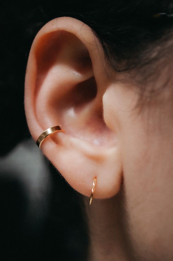 a woman's ear is shown with a gold ring on top of the ear