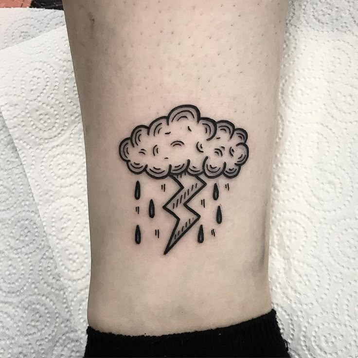 a black and white photo of a cloud with a lightning tattoo on the ankle