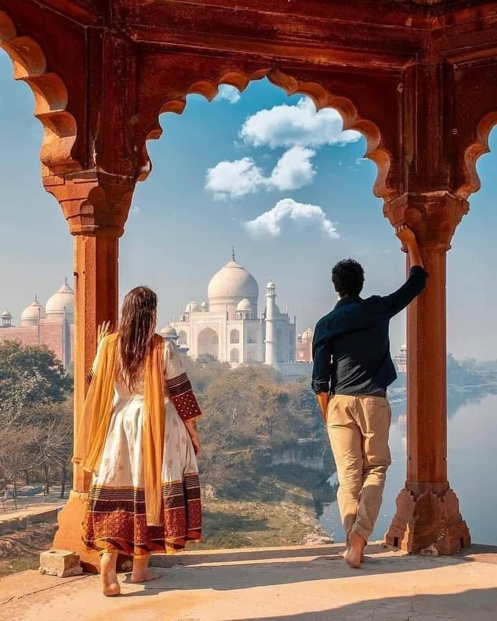 a man and woman looking out at the taj mahal from an archway in india