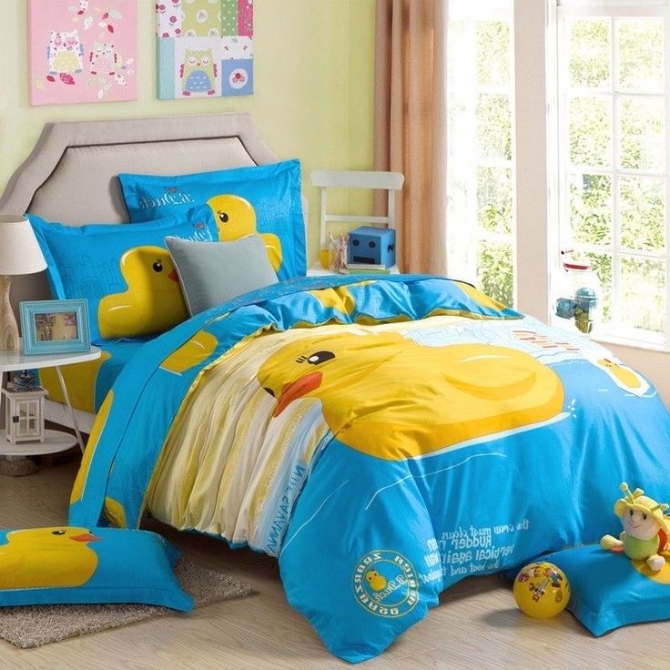 a child's bedroom with yellow and blue ducky comforters, pillows and toys