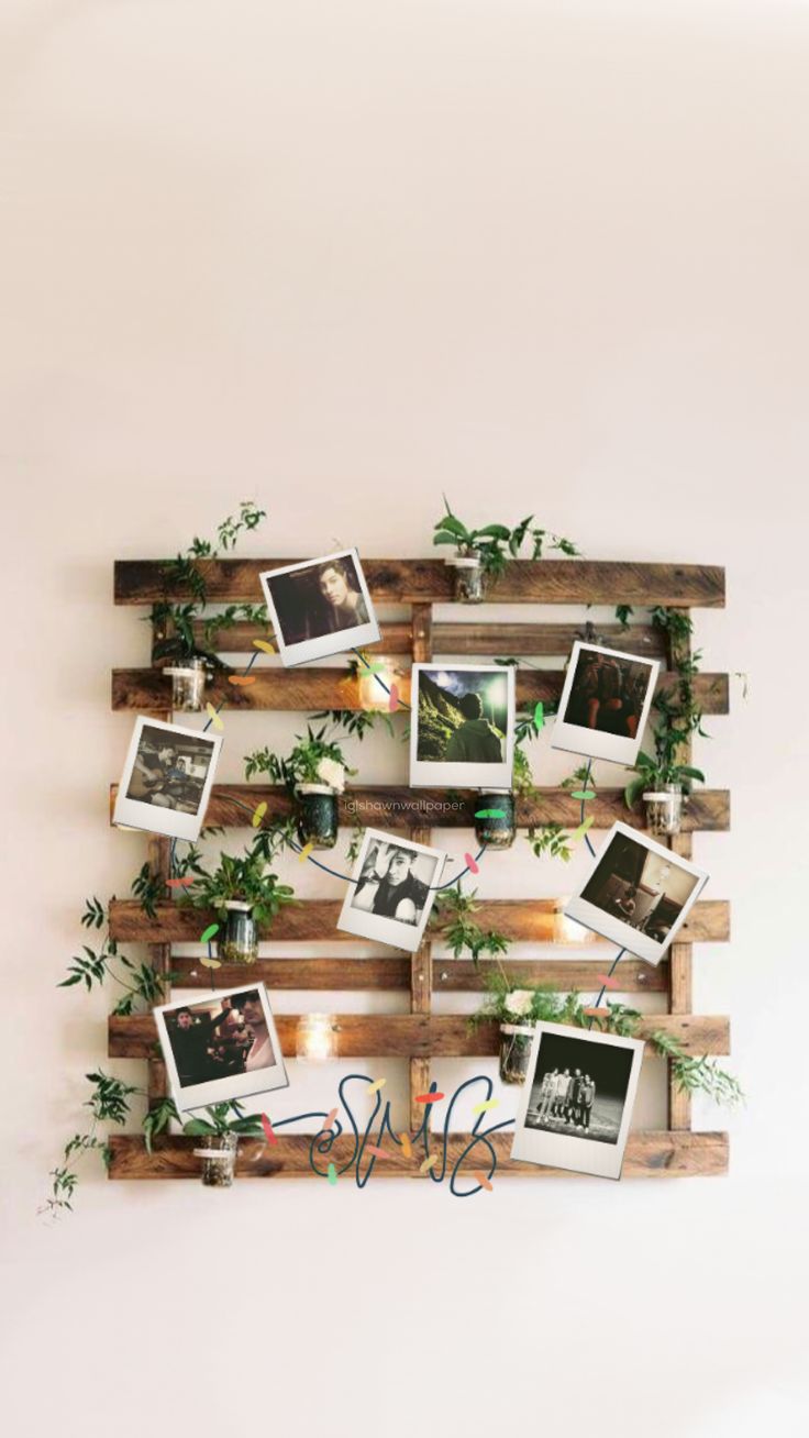 a wooden pallet filled with photos and greenery hanging on the side of a wall