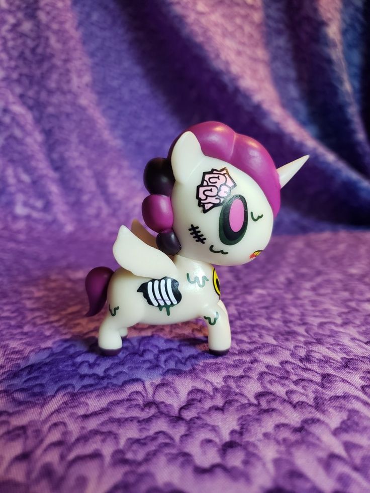 a small toy pony on a purple blanket