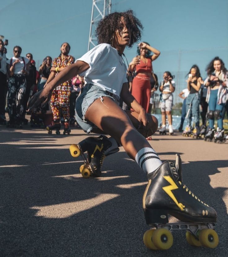 a woman riding a skateboard down a street next to other people onlookers