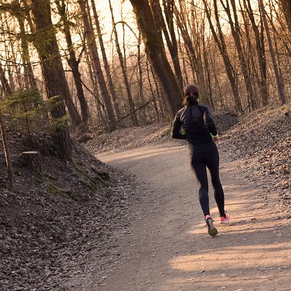 a woman running down a trail in the woods