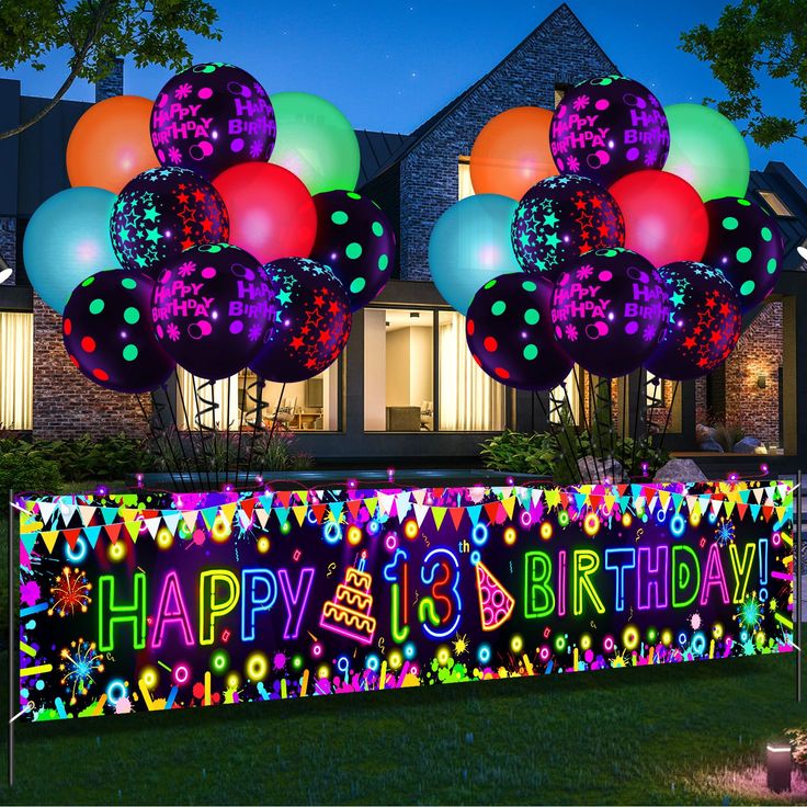 a birthday sign with balloons and streamers in front of a house at night time