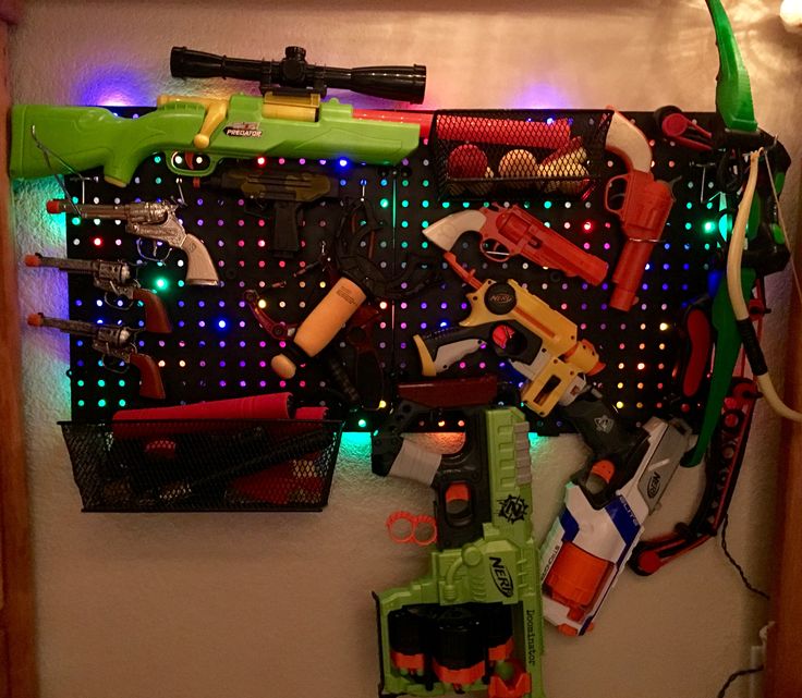 Mother & Son Sunday Fun! We designed and put together this backlit pegboard weapons wall! Luckily I knew exactly where I put the LED Christmas bulbs when I decided the plain old plastic pegboard was boring! After 30 min of trying to cram the lights behind the partially mounted boards I took the boards down and used duct tape to secure the lights and wires so they would be evenly distributed! Now to add two more pegboards because we only hung half of his weapons! Brag Board, Mother Son, Peg Board, Duct Tape, Boys Room, Boy's Room, I Decided, Bedroom Ideas, Mars