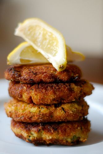 a stack of food on a plate with lemon wedges