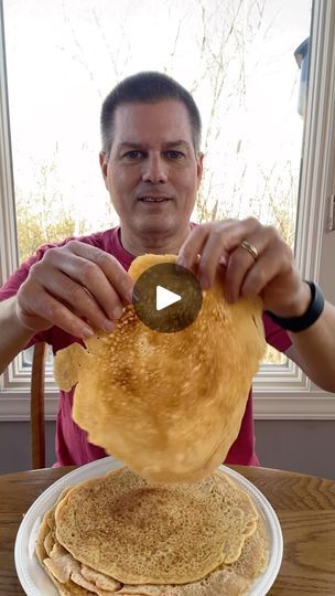 a man is making pancakes on top of a plate with a pancake in front of him