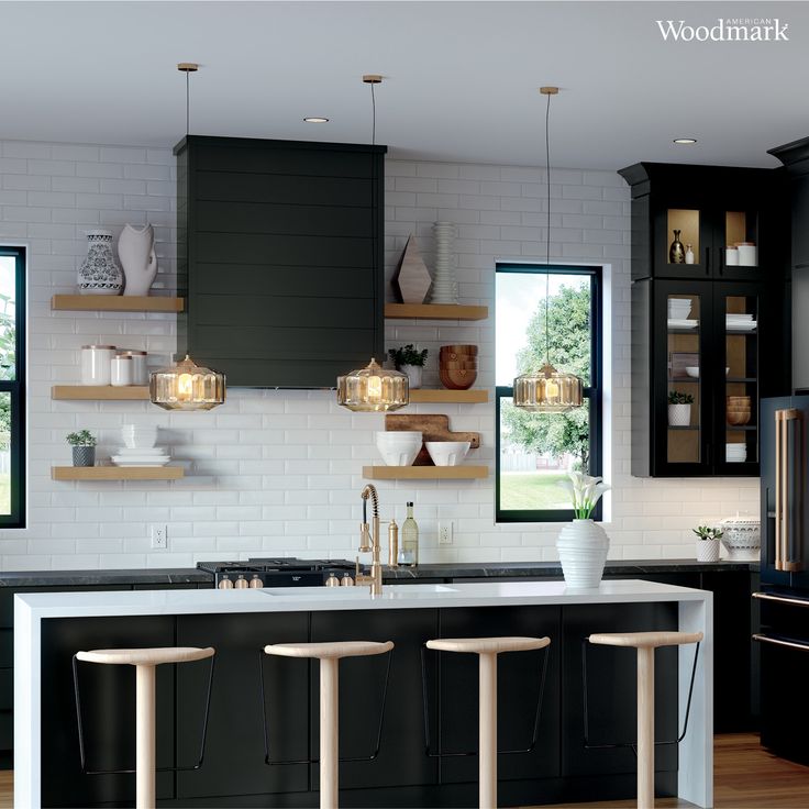 a modern kitchen with black cabinets and white counter tops, along with wooden stools