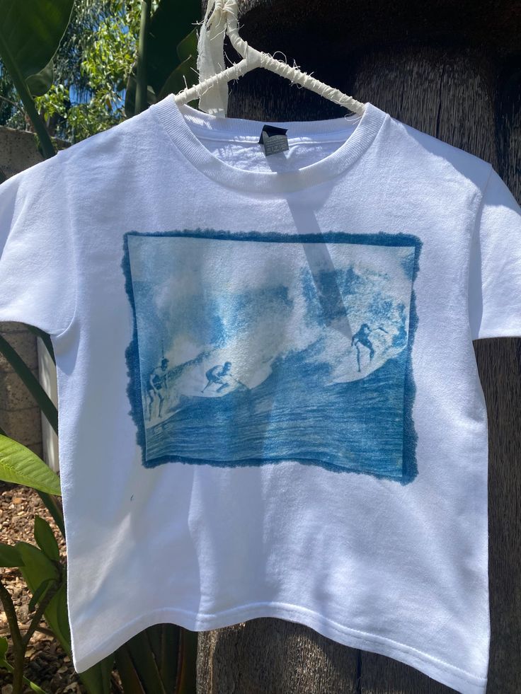 Handmade sun printed surfer t-shirt available as a babytee or regular fit for babytee please select "one size" (fits s/m) also available in regular sizes (s-xl) each shirt is made unique and not all will be the exactly the same but the print will be consistent  Wash instructions - Wash the fabric gently in cold water with a mild, pH-neutral detergent. Avoid using bleach or strong detergents, as they can degrade the print. -Avoid Direct Sunlight: Store the fabric away from direct sunlight when not in use. Prolonged exposure to strong light can cause fading over time. -Dry on cold setting or air dry.