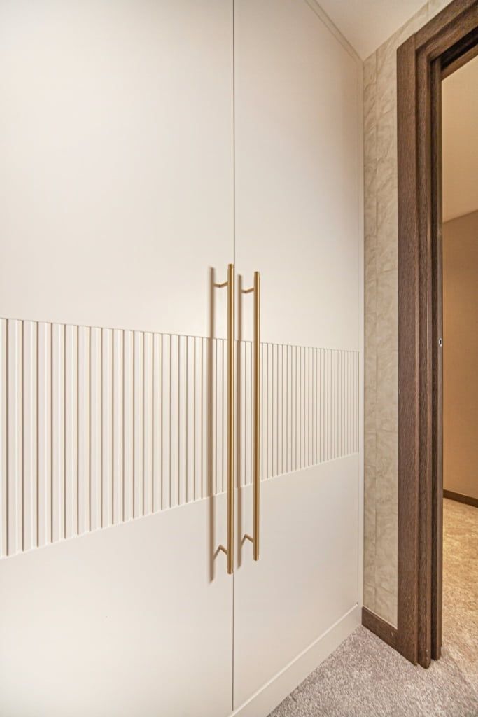 an empty hallway with white walls and gold handles on the doors, along with carpeted flooring