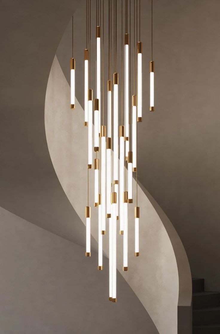 a modern chandelier with many lights hanging from it's sides and an artistic spiral staircase in the background