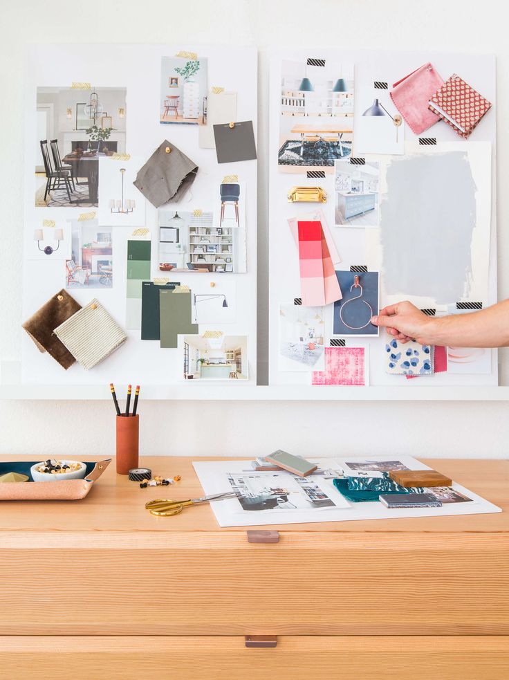 a person holding up a piece of paper on top of a wooden table next to a dresser