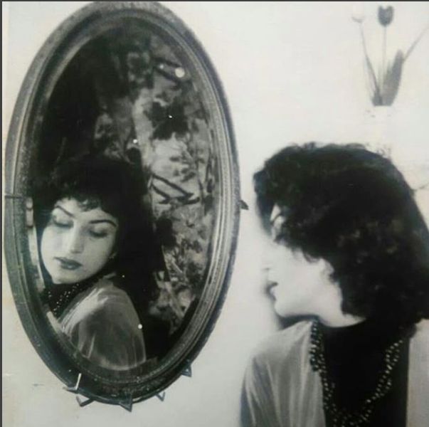 an old photo of a woman looking in the mirror with her face pressed against the wall