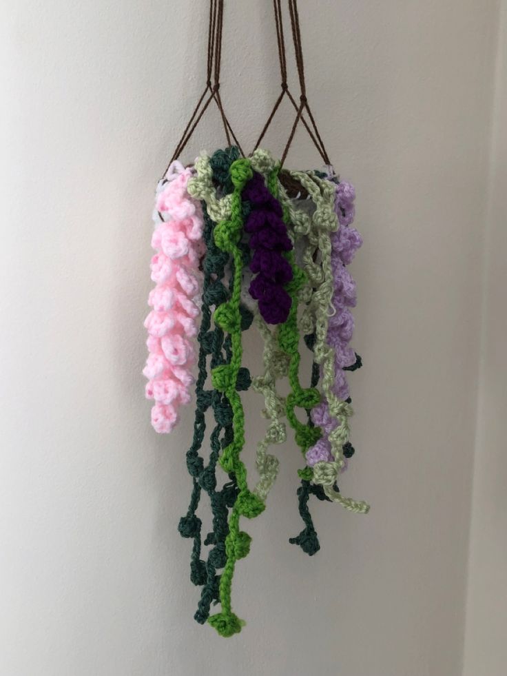 several crocheted flowers hanging from a hook on a wall in a room with white walls