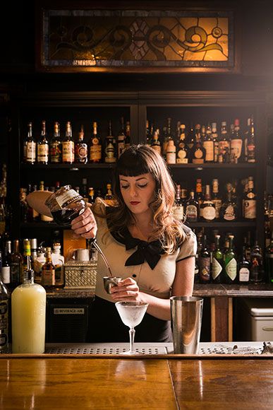 a woman is making a drink at the bar