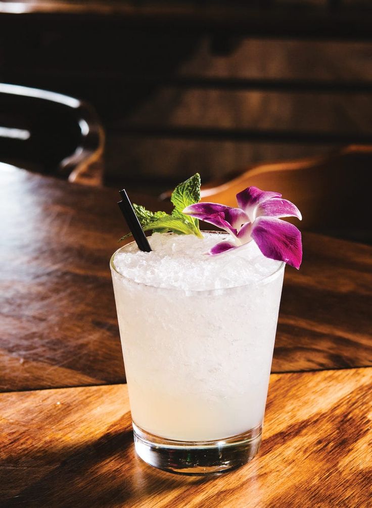 a tall glass filled with ice and a purple flower