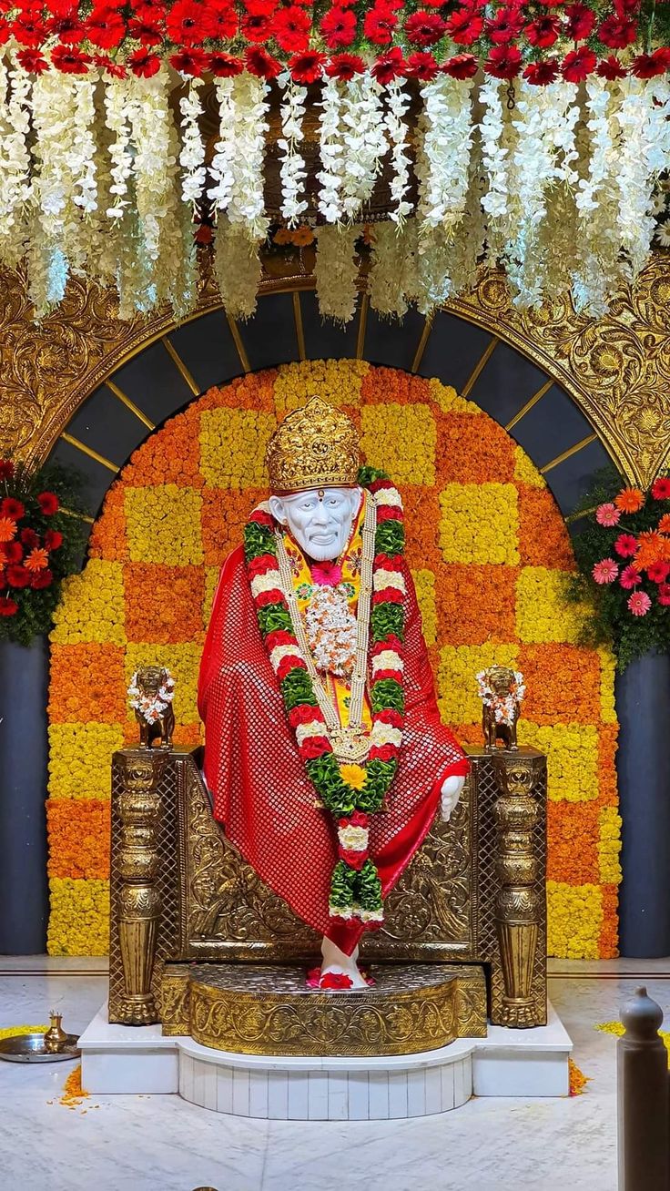 there is a statue in the middle of a stage with flowers all around it and garlands hanging from the ceiling