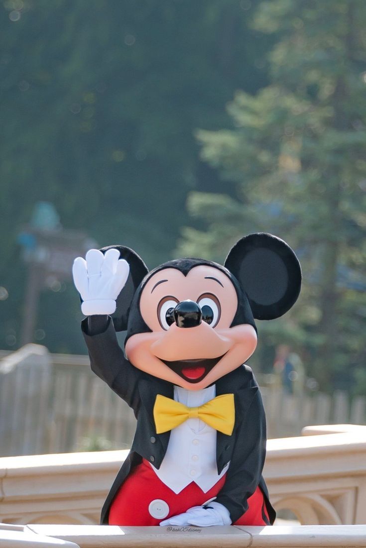 a mickey mouse mascot waving at the camera