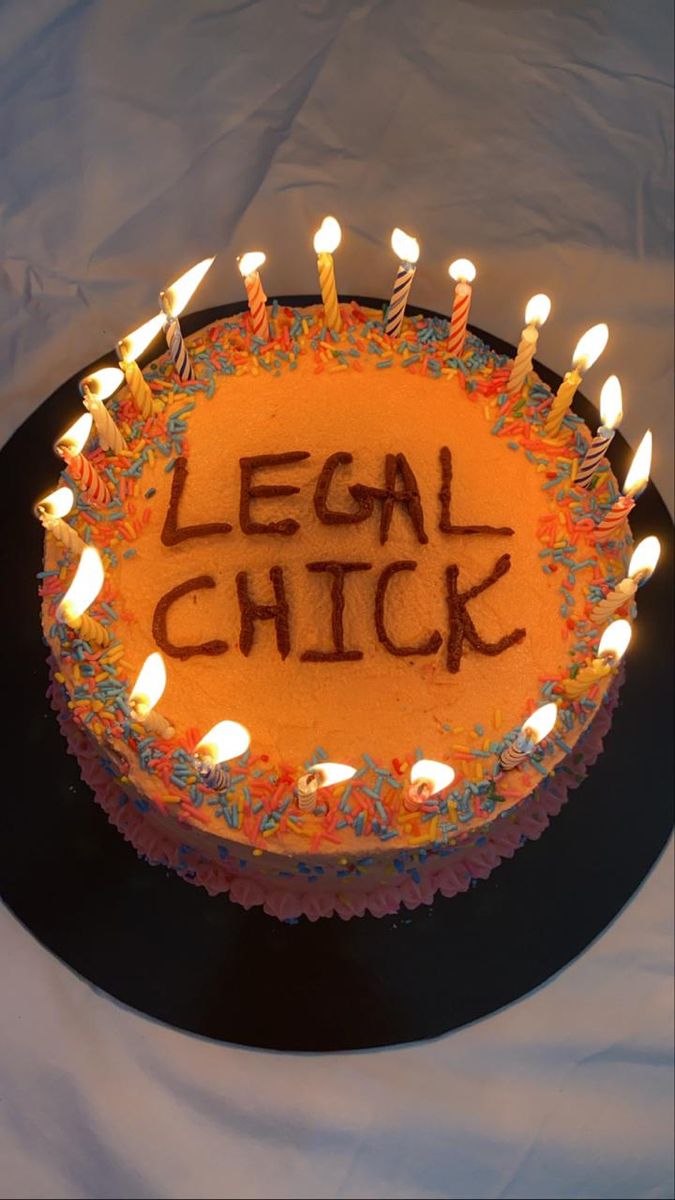 a birthday cake with lit candles and the words legal chick written on it