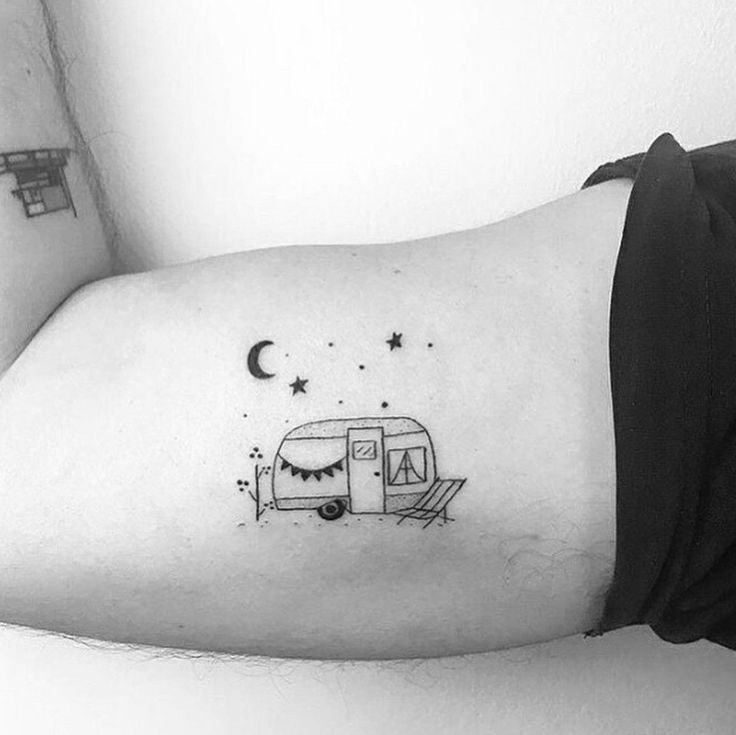 a black and white photo of a person's arm with a small camper tattoo on it