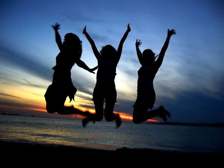 three girls jumping in the air at sunset