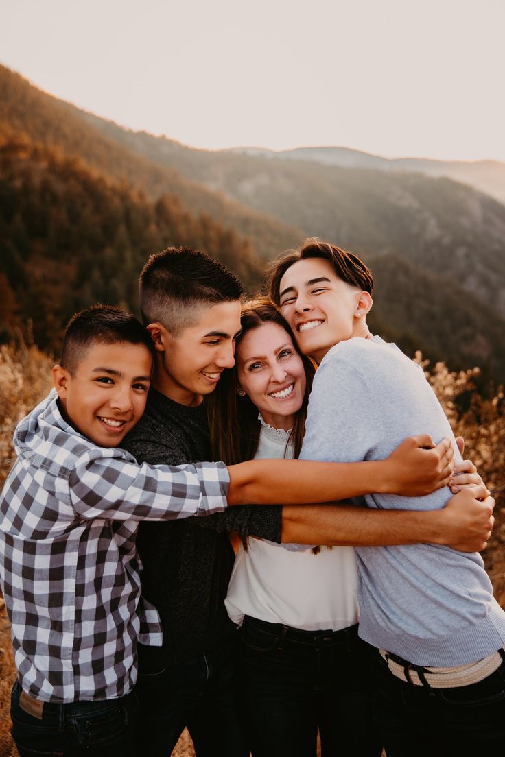 3 teenage boys snuggle up against their mom in front of a mountain valley backdrop. Teenage Family Photos Sibling Poses, Teenage Family Photoshoot Ideas, 4 Older Siblings Picture Ideas, Teenage Family Christmas Photos, Mom And Sons Photo Ideas Older, Older Family Photography Poses, Posing Family Of 4 With Teens, Teenage Family Photography, Mom And Teenage Sons Photo Ideas