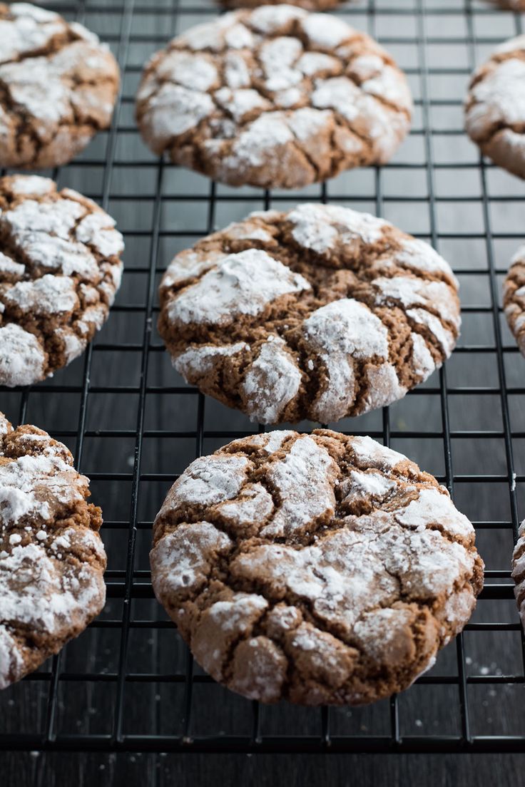 chocolate crinkle cookies cooling on a wire rack, with powdered sugar sprinkled on top