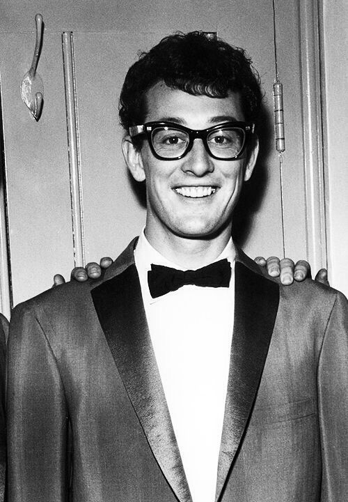 a man in a suit and bow tie standing next to another man with glasses on