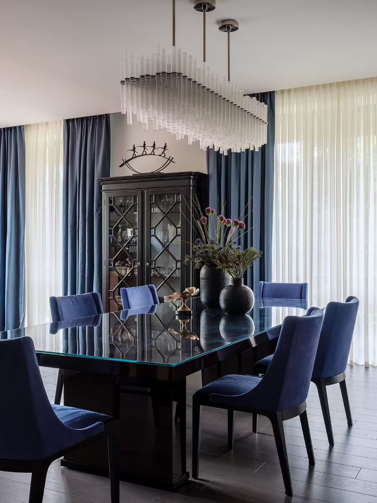 a dining room table with blue chairs and a glass top centerpiece in the middle