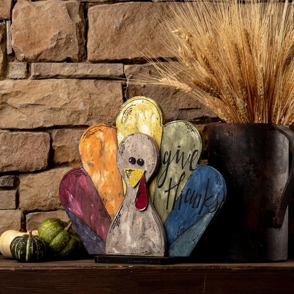 a wooden turkey sitting on top of a table next to a potted plant and some gourds