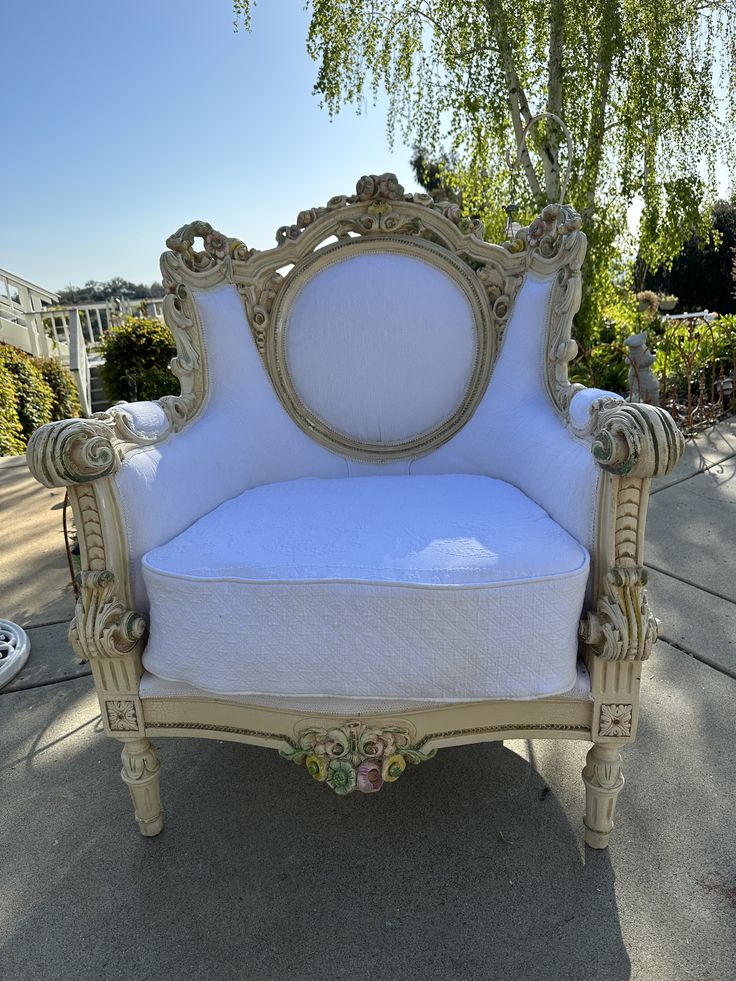 an antique style chair with white upholstered cushions