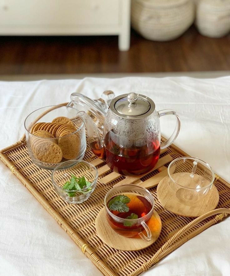 a tray with tea, cookies and fruit on it sitting on top of a bed