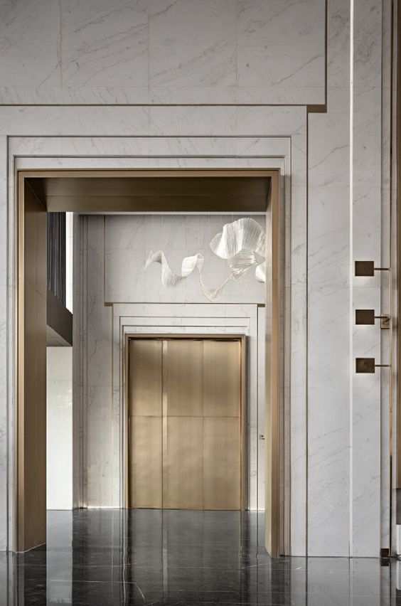 an open door leading into a room with marble walls and flooring on either side