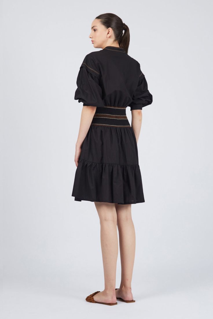 Elevate your style with the Mercy Dress, a perfect blend of elegance and comfort. Crafted from 100% cotton, this mini dress is available in striking blue and classic black, making it a versatile addition to your wardrobe. The pleated ruffled skirt adds a playful touch, while the elasticated belt with contrasting stitching defines your silhouette effortlessly. Featuring a shirt collar V-neckline, buttoned chest, and long sleeves with dropped shoulder details, the Mercy Dress offers both sophistic Chic Pleated Mini Dress For Daywear, Pleated Voluminous Tiered Skirt Dresses, Chic Pleated Tiered Skirt Dress, Cotton Ruffle Dress With Mini Length, A-line Mini Dress With Ruffle Hem For Daywear, Cotton Mini Dress With Ruffle Hem For Daywear, Chic Black Mini Dress With Pleated Hem, Chic Black Mini Dress With Tiered Skirt, Chic Cotton Midi Dress With Ruffle Hem