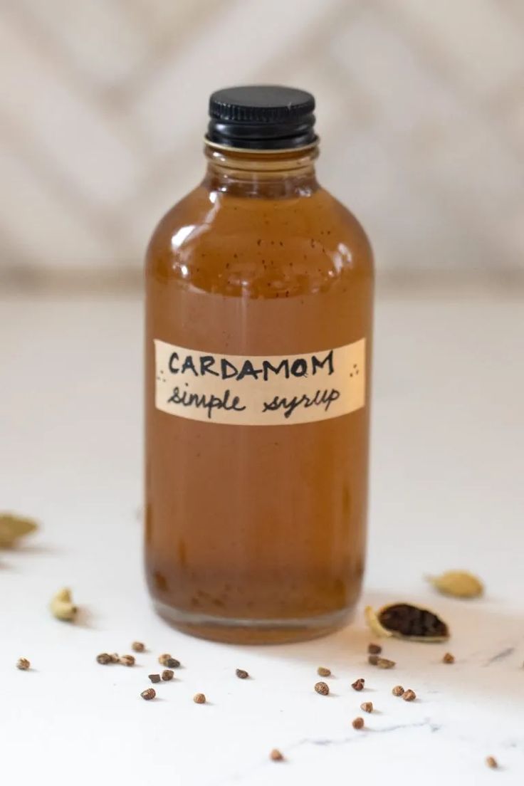 a bottle filled with liquid sitting on top of a white counter next to some seeds