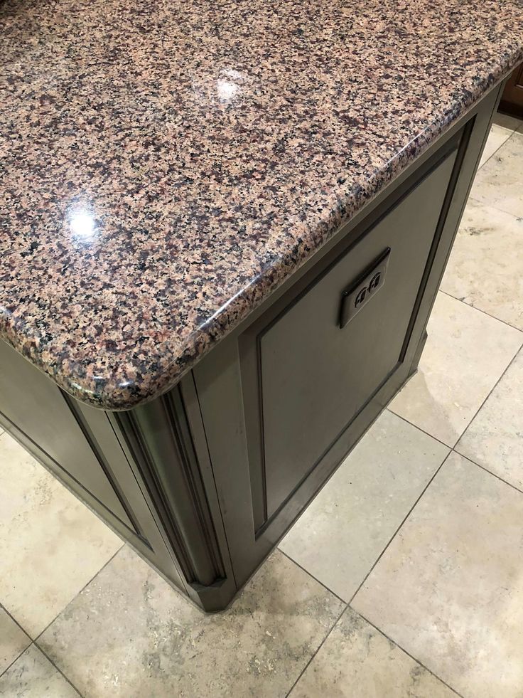 a granite counter top in a kitchen with tile flooring and cabinets on the side