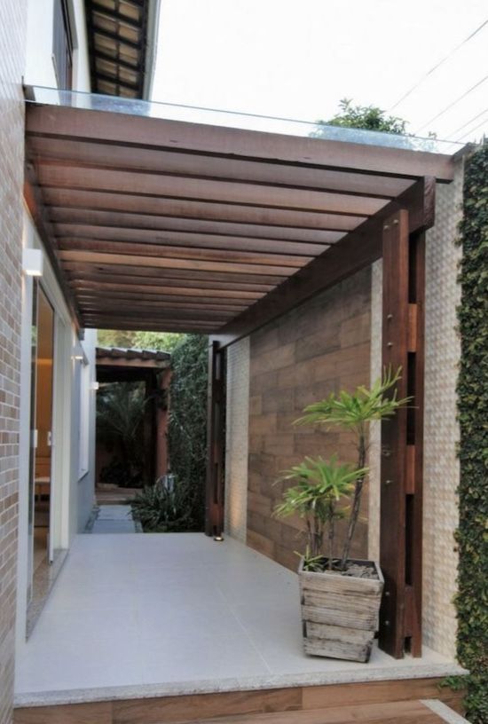 an outdoor covered patio with potted plants on the floor and brick wall behind it