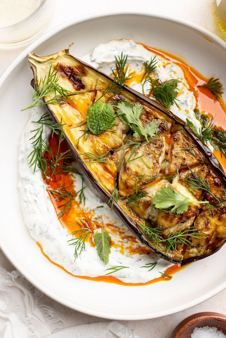 an eggplant dish on a white plate with orange sauce and garnish