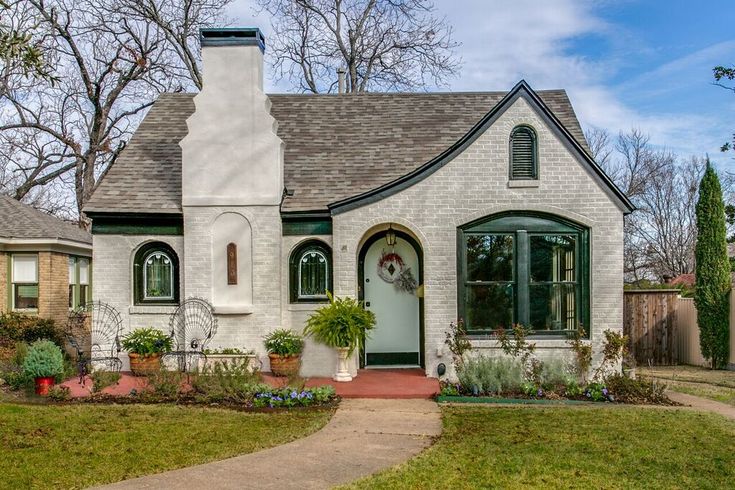 a white brick house with green trim and windows