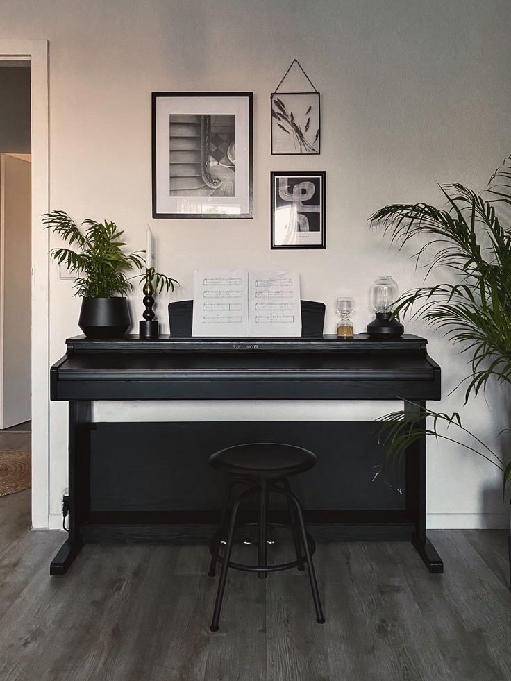 there is a piano in the room with plants on the table and pictures above it