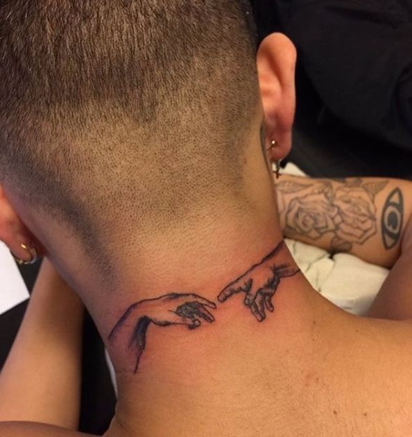 a tattoo on the back of a man's neck with two hands pointing at each other