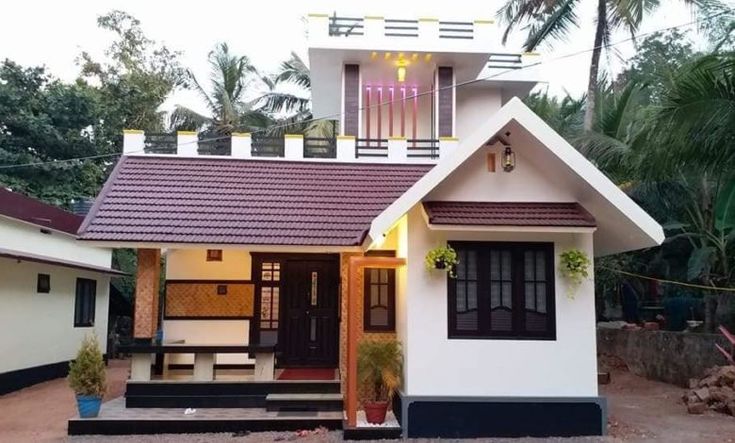 a small white house with a red roof and black shutters on the front door