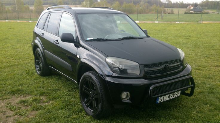 a black suv parked on top of a lush green field