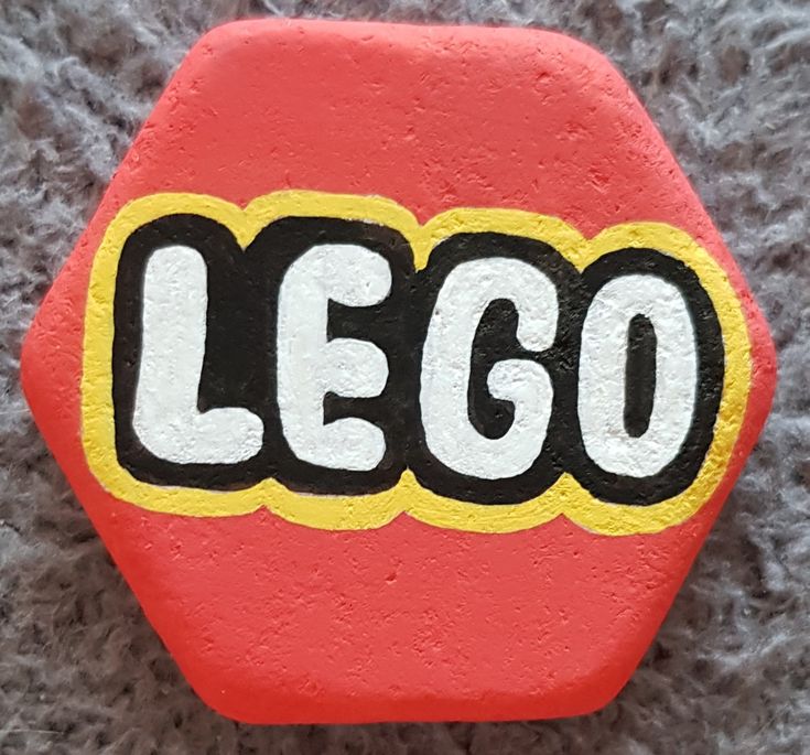 a close up of a red and yellow lego logo on a gray carpeted surface