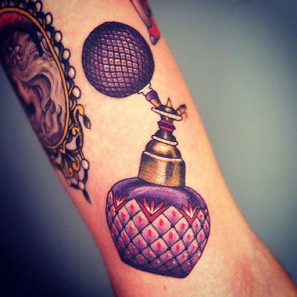 a person with a tattoo on their arm has a perfume bottle in the shape of a heart