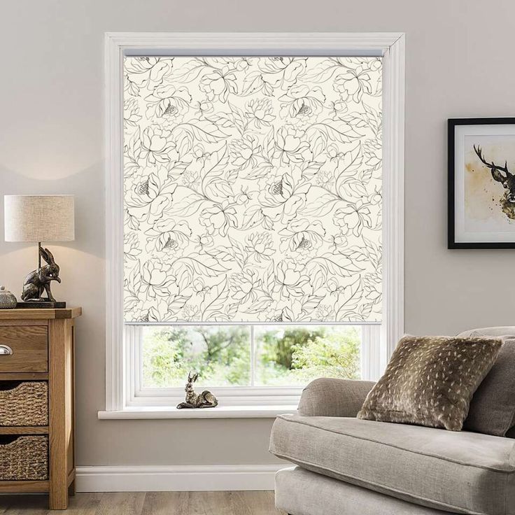 a living room with a couch, chair and window covered in roman blind blinds that have floral designs on them