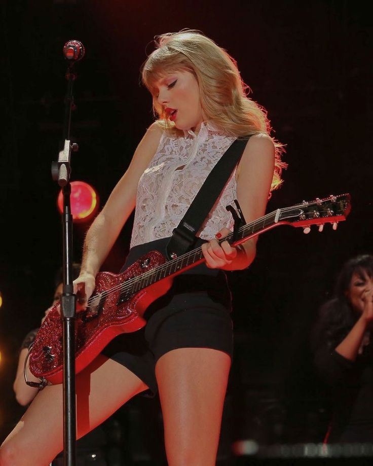 taylor swift performing on stage with her guitar