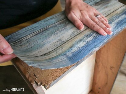 a person is holding something on top of a piece of wood that has been painted blue