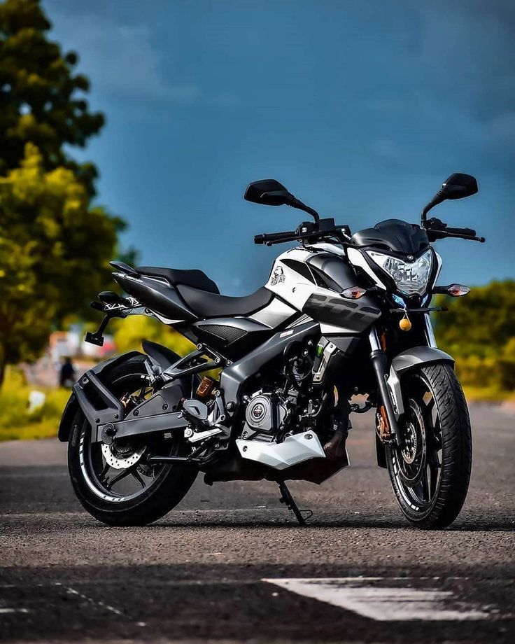 a black and white motorcycle parked on the side of the road with trees in the background